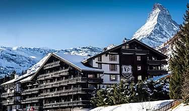 Hôtel enneigé dans les Alpes devant le Matterhorn.