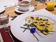 Omelette with vegetables on a white plate, served on a set breakfast table.