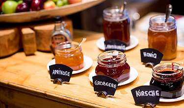 Plusieurs verres avec différents confitures de fruits sur une table en bois.
