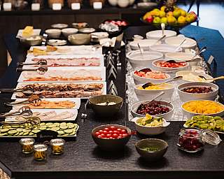 Buffet avec des fruits, du yaourt, de la charcuterie, des légumes et des sauces sur une table dressée