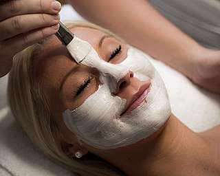 Femme avec un masque blanc sur le visage lors d’un soin cosmétique