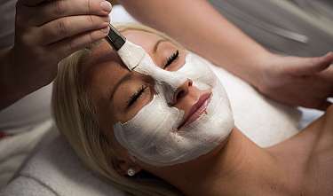 Femme avec un masque facial blanc lors d'un soin cosmétique