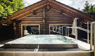 Cabane en bois avec jacuzzi bouillonnant à l'extérieur et des arbres autour