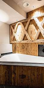 Modernes Badezimmer mit freistehender Badewanne, Holzvertäfelung und dunkler Steinablage.