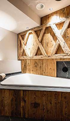 Salle de bain moderne avec baignoire îlot, lambris en bois et tablette en pierre sombre.