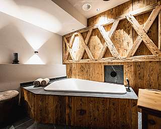 Salle de bains moderne avec baignoire îlot, revêtement en bois et surface en pierre sombre.