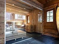 Modern sauna with wooden fittings, glass front and gold floor lamp.