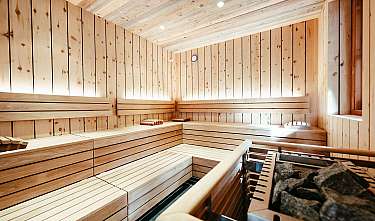 Intérieur d’un sauna en bois clair avec des bancs et un poêle