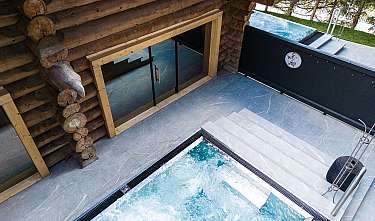 Vue d'un espace bien-être avec façade en bois, piscine, escalier et terrasse.
