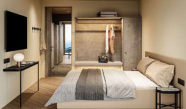 Modernes Schlafzimmer mit Bett, Wandfernseher, Garderobe und Nachttischen.
