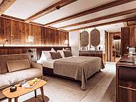 Modernes Schlafzimmer mit Holzwänden, Bett, Sofa und stilvoller Beleuchtung.