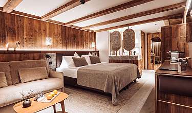 Chambre moderne avec revêtement en bois, lit, canapé et lampes décoratives.