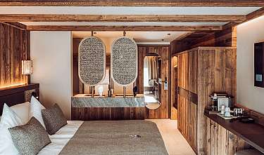 Chambre d’hôtel confortable avec des meubles en bois, un lit double et une cloison décorative.