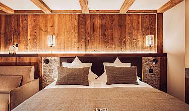 Chambre confortable avec lit double, revêtement en bois et lampes chaleureuses.
