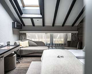 Modernes Schlafzimmer mit Sessel, Schreibtisch und Dachfenster.