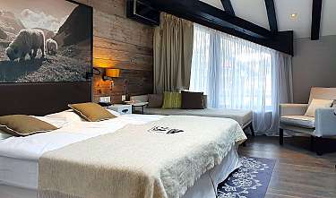Modernes Schlafzimmer mit Bett, Sitzgelegenheit, Holzvertäfelung und großem Fenster mit Vorhängen.