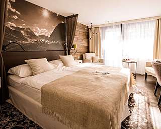Chambre d’hôtel moderne avec lit double, coin salon et grandes fenêtres.