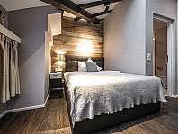 Modernes Hotelzimmer mit zwei Betten, Schreibtisch, großem Fenster und Spiegelwand.