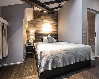 Modernes Hotelzimmer mit zwei Betten, Schreibtisch, großem Fenster und Spiegelwand.