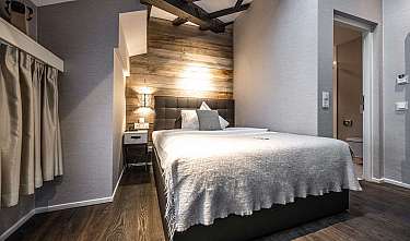 Modern eingerichtetes Schlafzimmer mit Bett, Holzpaneel-Wand und warmen Wandleuchten.