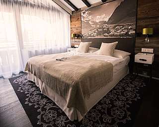 Chambre moderne avec lit double, panneaux en bois et grande œuvre murale au-dessus de la tête de lit.