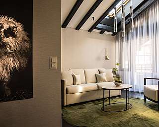 Bright living room with sofa, armchair, coffee table and large sheep portrait on the wall.