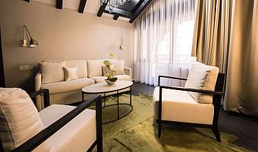 Bright, modern-furnished living room with sofa, armchairs, coffee table and large windows.