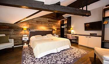 Cosy bedroom with wooden wall, double bed, desk and wall-mounted TV.