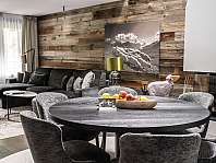 Modern eingerichteter Wohn- und Essbereich mit Holzwand, Sofa, Esstisch und Dekoration.