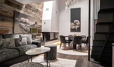 Modern living room with sofa, coffee tables, dining table and large wall pictures.