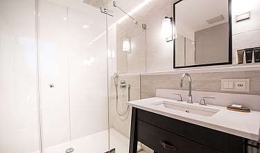 Bright modern bathroom with glass shower, washbasin, mirror and wall lighting.