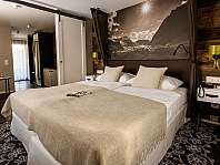 Ein stilvoll eingerichtetes Hotelzimmer mit Doppelbett, Nachttischen und Bergmotiv an der Wand.