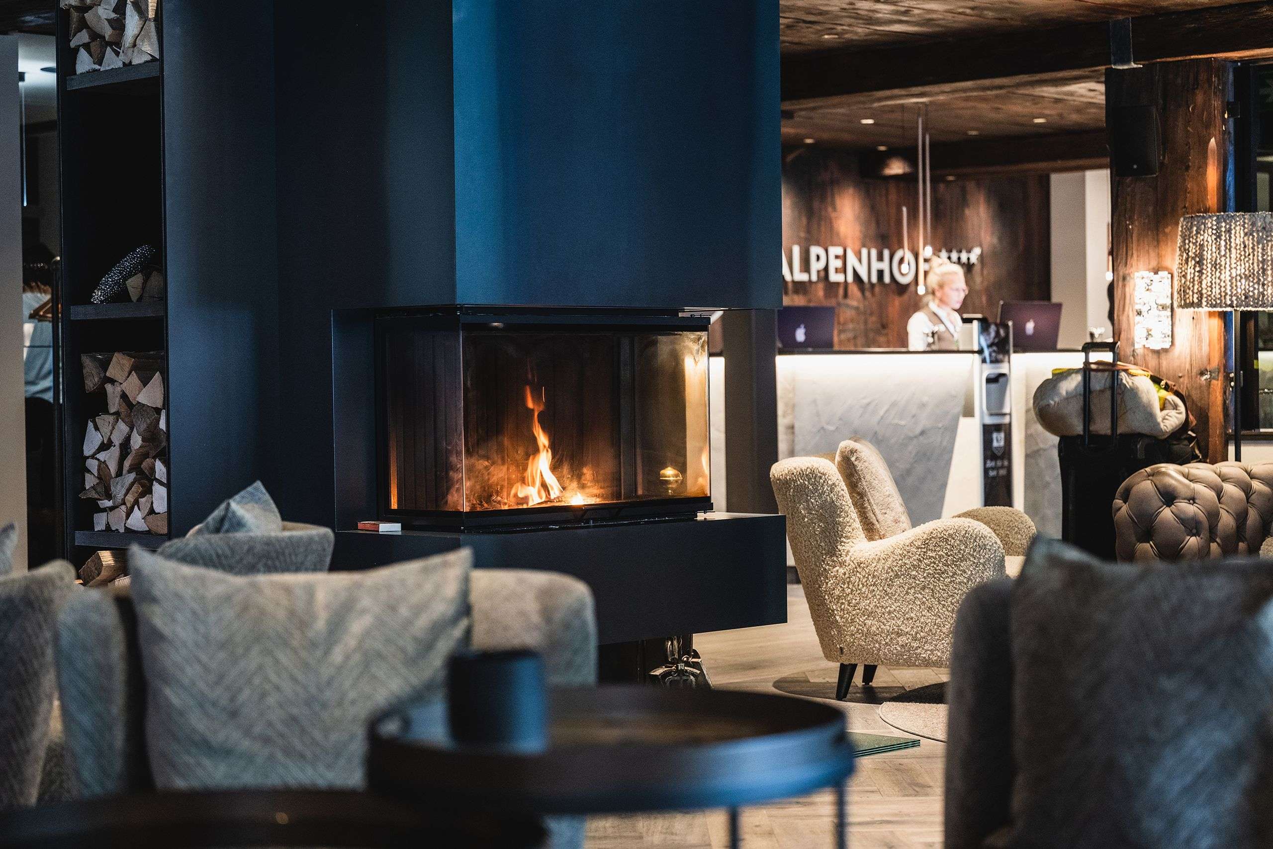 Stilvolle Hotel Lobby mit brennendem Kamin, Sesseln und Empfangstresen.
