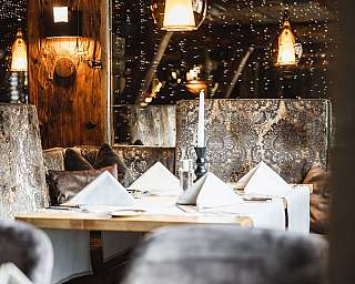 Gemütliches Restaurant mit gedeckten Tischen, gepolsterten Sitzen und warmen Hängeleuchten.