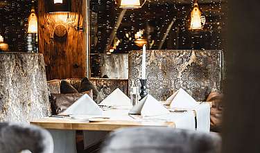 Gemütliches Restaurant mit gedeckten Tischen, gepolsterten Sitznischen und warmen Pendelleuchten.