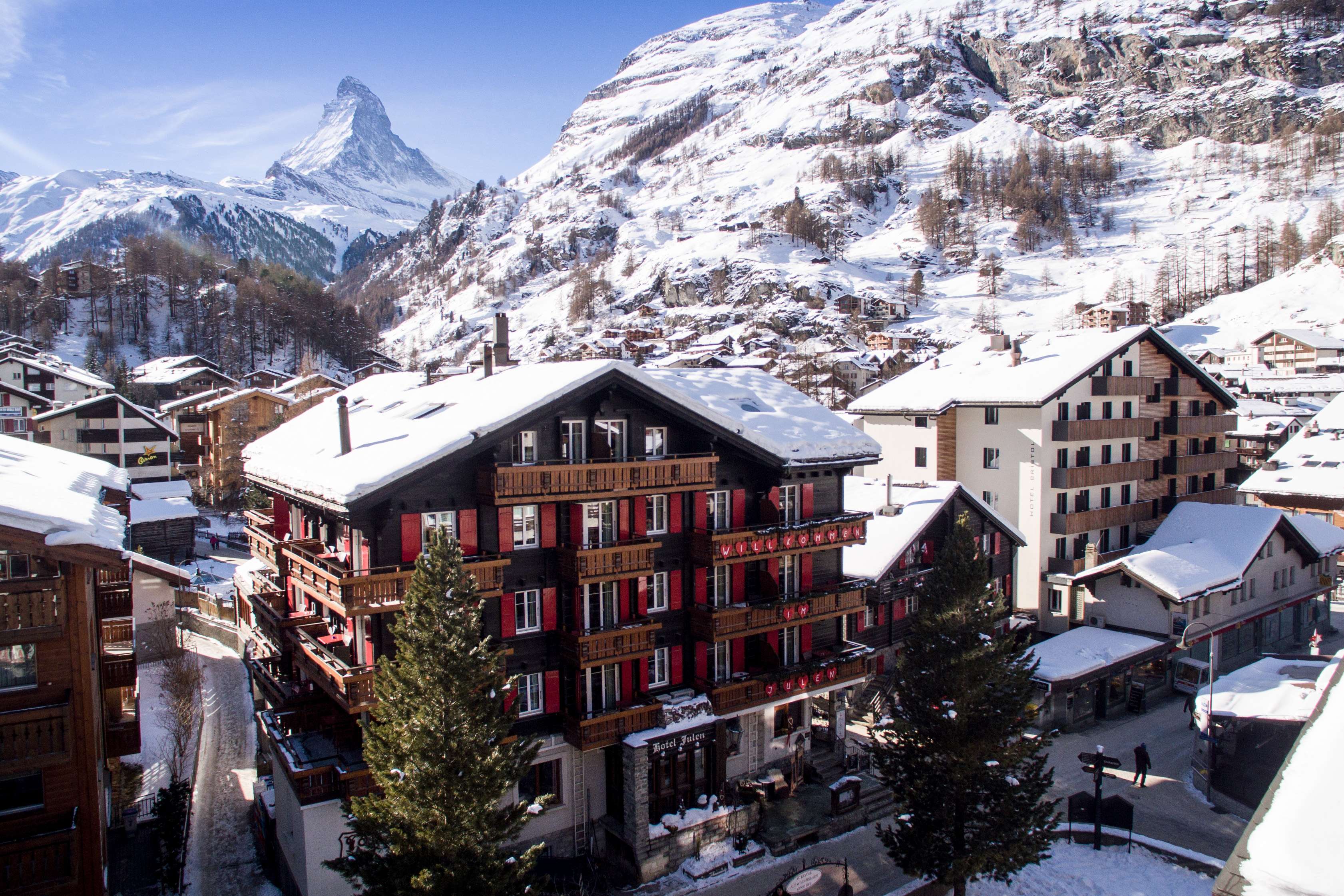 Village enneigé avec des chalets devant un décor de montagnes alpines