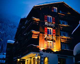 Wooden hotel in a snow-covered mountain village with lit windows at night