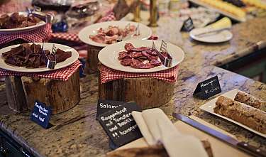 Buffet with various cold cuts on plates and wooden stands