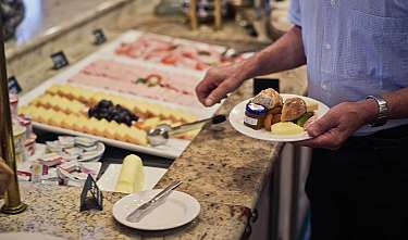 Man holding a plate with breakfast side dishes at the buffet.