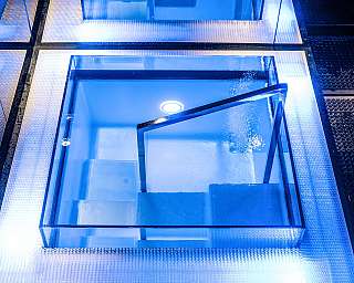 Installation en verre bleue avec une boîte en verre ouverte et des surfaces éclairées.