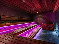 Innenraum einer modernen Sauna mit Holzsitzen und violetter LED-Beleuchtung