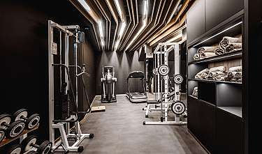 Salle de fitness aménagée de façon moderne avec des appareils d'entraînement, des haltères et des serviettes sur des étagères.