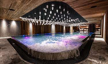 Piscine intérieure moderne avec bord en cascade, plafond en bois et suspensions en verre.