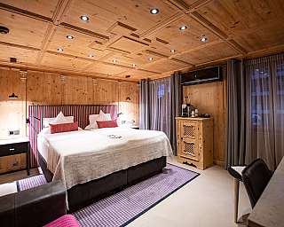 Chambre à coucher moderne avec murs en bois, lit double, rideaux et lumière chaude.