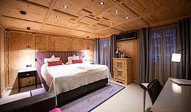Chambre lumineuse avec lit double, revêtement en bois, tables de chevet et rideaux.
