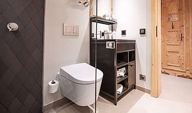 Salle de bains moderne avec WC mural, douche sombre et meuble en bois