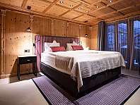 Chambre moderne avec lit double, lambris en bois et grandes fenêtres.