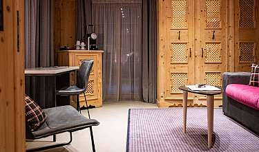 Salon confortable avec meubles en bois, canapé, chaises et petite table basse.