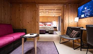 Chambre d'hôtel confortable avec revêtement en bois, canapé, télévision et vue sur le lit.