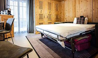 Chambre revêtue de bois avec lit escamotable, bureau et baie vitrée.